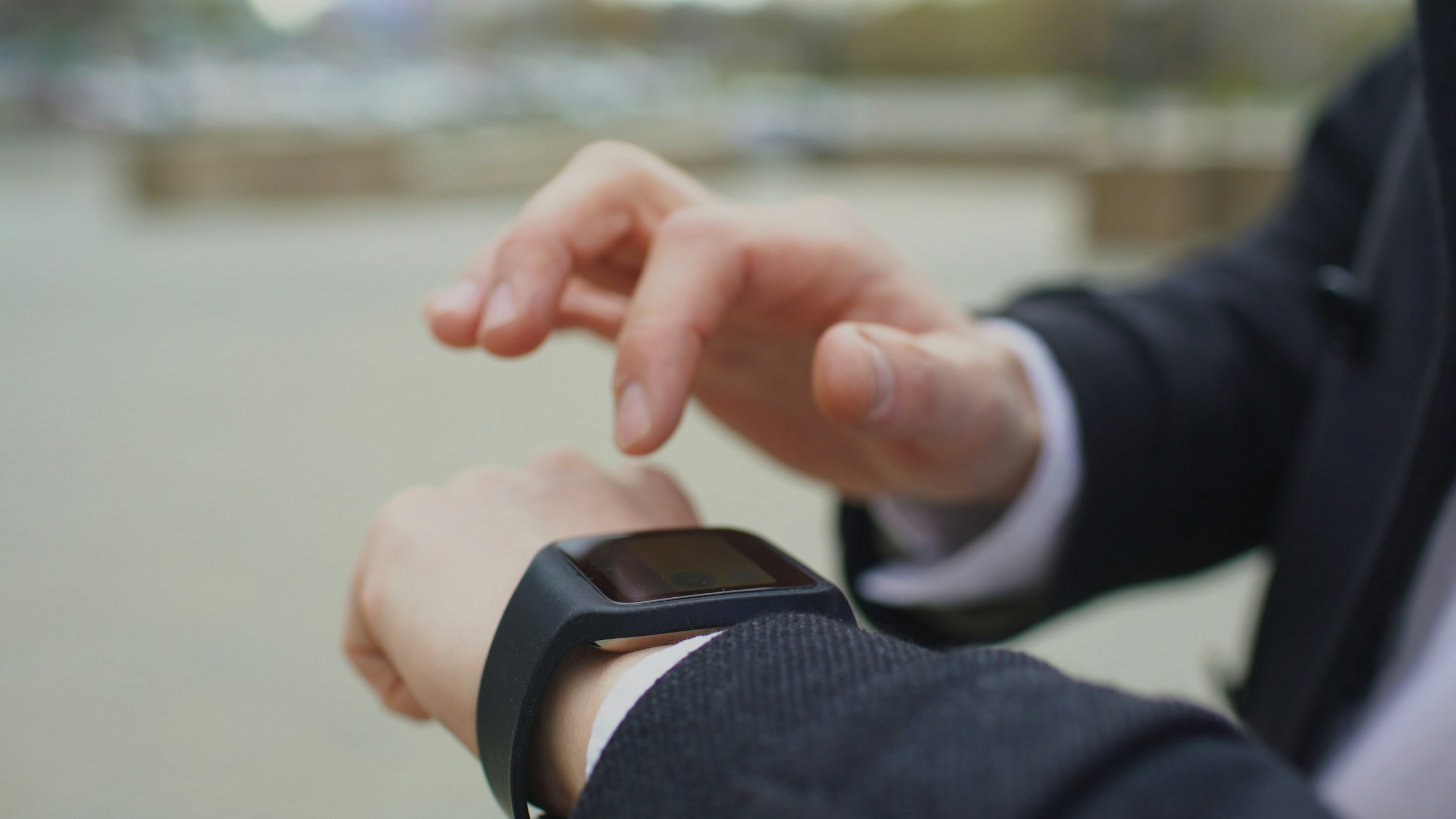 Closeup of businessman using his smartwatch touchscreen standing on street measuring productivity