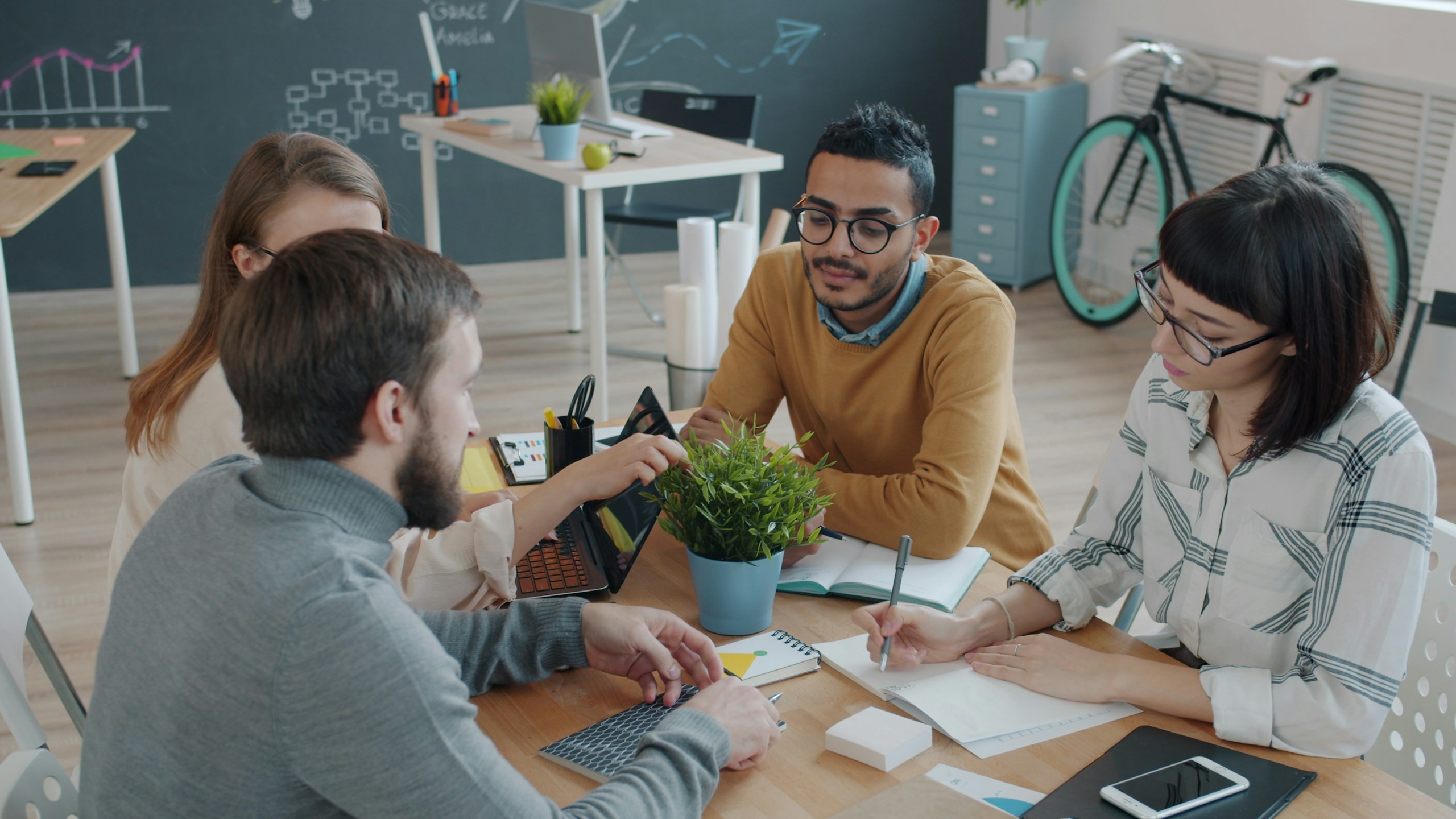 Joyful colleagues mixed race men and women are talking at desk in office then doing high-five and laughing. Collaboration, people and business concept.